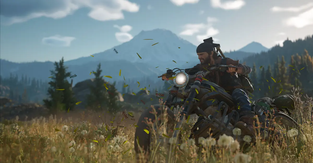 Deacon St. John alla guida della sua moto da randagio pesantemente modificata attraverso una lussureggiante ma pericolosa foresta del Pacifico nord-occidentale in Days Gone.
