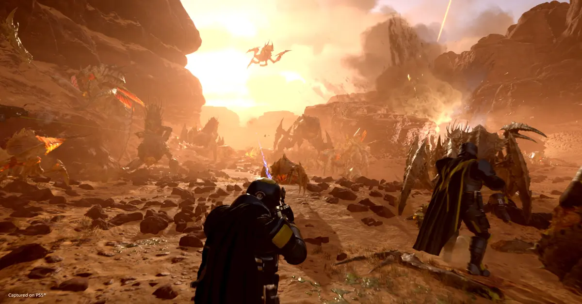 Soldati di Helldivers 2 si lanciano in un infuocato campo di battaglia alieno durante un combattimento intenso